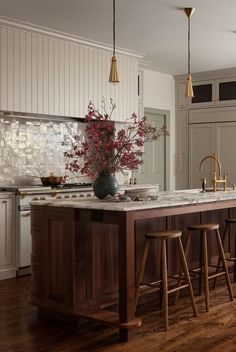 a kitchen island with stools next to it and a vase on the counter top