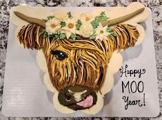 a cake decorated to look like a cow with flowers on its head and the words happy moo year