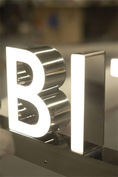 the letters b and i are lit up in front of a metal object that is sitting on top of a table