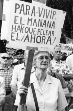 an old woman holding a sign in front of a group of people with signs that read para - vir, el - mana