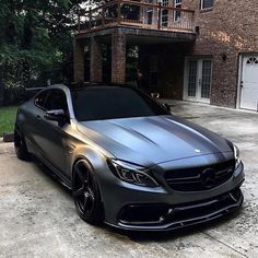 a mercedes benz is parked in front of a house with two garage doors on the side