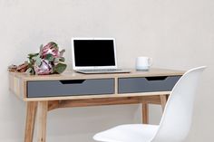 a laptop computer sitting on top of a wooden desk next to a white plastic chair