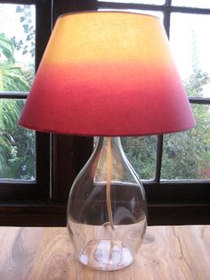 a lamp that is on top of a table next to a glass vase with water in it