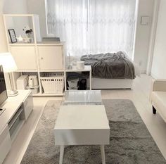 a living room filled with furniture and a white table in front of a tv on top of a hard wood floor