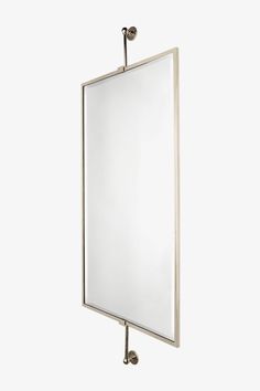 a mirror mounted to the side of a white wall with a metal hook on it