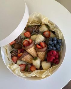 a bowl filled with strawberries, blueberries and raspberries in ice cream cones