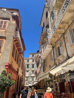 people are walking down an alley way in the city with buildings and balconies