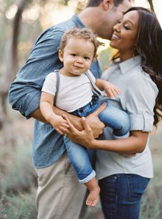 a man and woman holding a baby in their arms