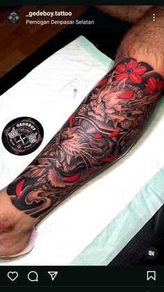 a man with a dragon tattoo on his arm and leg next to a white table