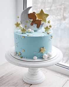 a blue cake with gold stars and a teddy bear on top