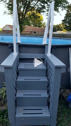 the steps leading up to an above ground pool are painted gray and have white railings