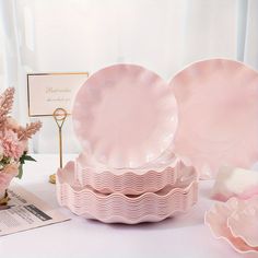 there are pink plates and flowers on the table