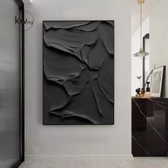 a black abstract painting hangs on the wall