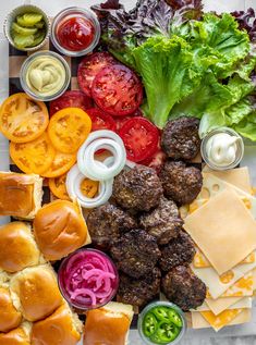 a platter with meatballs, tomatoes, lettuce, cheese and sauces