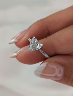 a woman's hand holding an engagement ring with a diamond on the middle finger