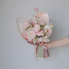 a person holding a bouquet of flowers with a tag attached to the front of it