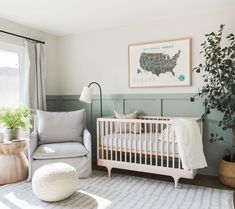 a baby's room with a crib, chair and potted plant