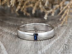 a silver ring with a blue stone in the center on a wooden table next to some branches