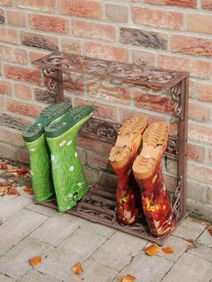 two pairs of green boots are sitting on a rack in front of a brick wall