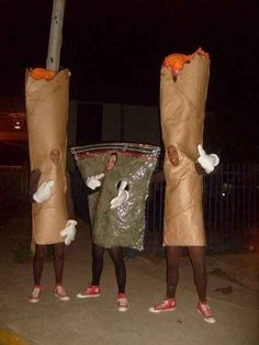 three people dressed up as carrots with bags on their heads and legs, standing in the street at night