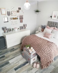 a bedroom with white walls and wood flooring is decorated in pink, gray and grey tones