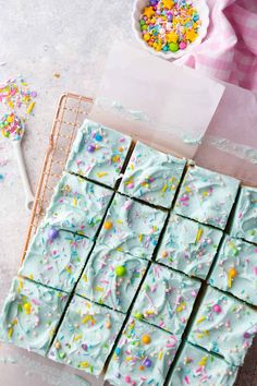 blue frosted squares with sprinkles on a cooling rack next to a spoon