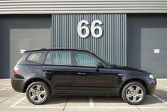 a black car parked in front of a building with the number 66 on it's side