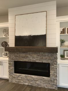 a fireplace with white cabinets and a painting on the wall above it's mantle