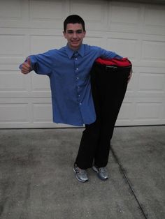 a man in blue shirt and black pants standing next to a garage door with his arms out