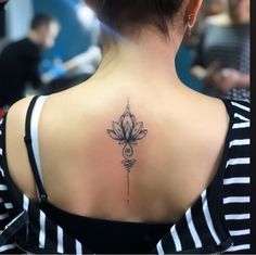 a woman's back with a lotus tattoo on her left shoulder and an arrow in the middle