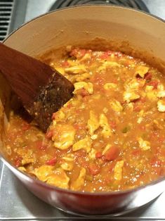 a pot filled with food sitting on top of a stove next to a wooden spoon