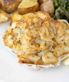 a white plate topped with food next to potatoes and broccoli