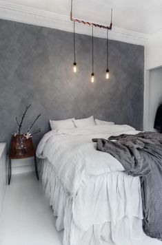 a white bed sitting in a bedroom next to two lights hanging from the ceiling above it