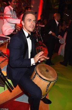 a man in a tuxedo is holding a drum