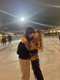 a man and woman hugging on an ice rink