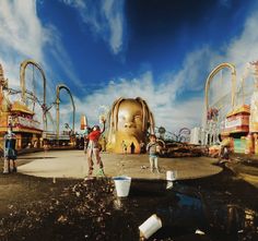 two people are standing in front of an abandoned roller coaster at a carnival or amusement park