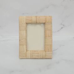 a square frame made out of bamboo on a white marble countertop, with the top section