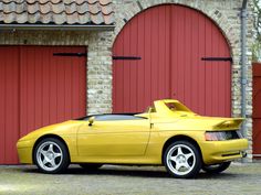 a yellow sports car parked in front of a red garage door