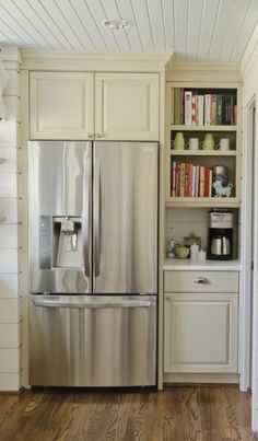 a stainless steel refrigerator freezer sitting in a kitchen next to white cabinets and wooden floors