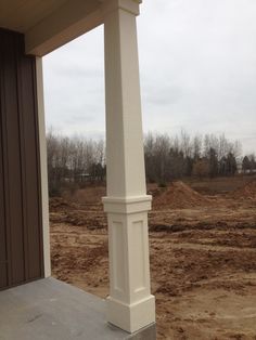 a large white pillar sitting on top of a cement floor next to a dirt field