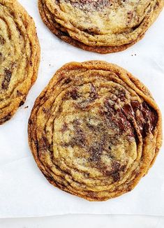 three chocolate chip cookies sitting on top of white paper