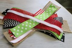 a cross made out of fabric on top of a white table with red and green ribbons