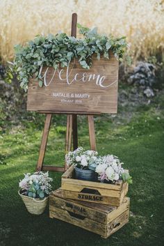 a welcome sign with flowers and greenery is displayed in front of two wooden crates