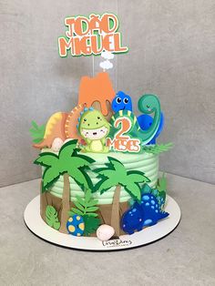 a birthday cake decorated with dinosaurs and plants