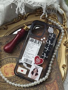 a cell phone case sitting on top of a table next to pearls and a pen