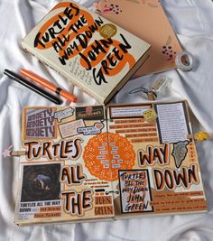 an open book with writing on it next to some other books and papers that are laying on a bed