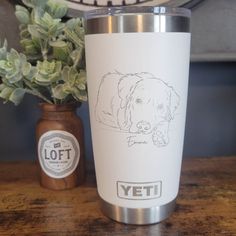 a cup with a drawing of a dog on it next to a potted plant