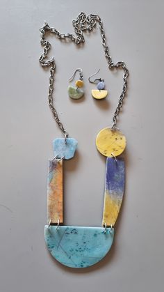 a necklace and earring set made out of marbles on a metal chain with two disc pendants hanging from it