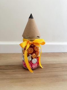 a jar filled with candies and candy on top of a wooden table next to a white wall