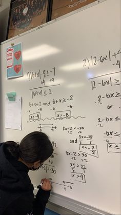 a woman writing on a white board with numbers